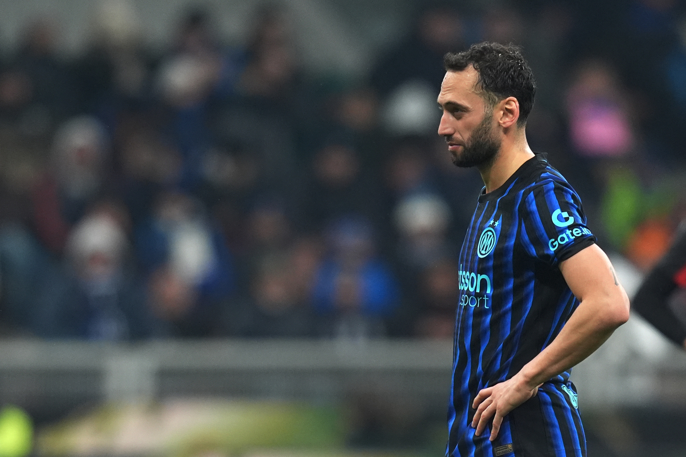 Hakan Calhanoglu in campo con le mani sui fianchi durante una pausa di gioco, in attesa di aggiornamenti sulle sue condizioni fisiche